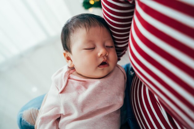 gros plan belle petite fille asiatique dormant paisiblement sur la poitrine de sa mère. femme tenant son mignon nouveau-né qui s'endort.