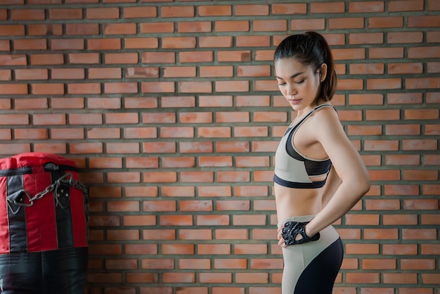 Gros plan sur une belle sportive asiatique porter un soutien-gorge de sport sur le mur de la salle de sportThailand love healthSlim woman workout concept