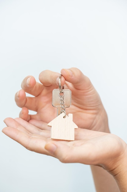 Gros plan de belles mains d'une femme avec les nouvelles clés de la maison. Porte-clés en forme de maison en bois