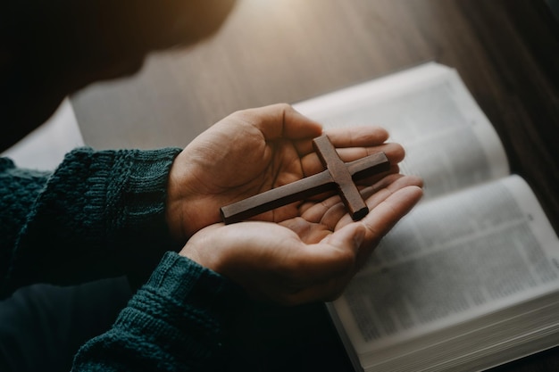 Gros plan d'une bible ouverte avec une croix pour la dévotion du matin sur une table en bois avec des lumières de fenêtre