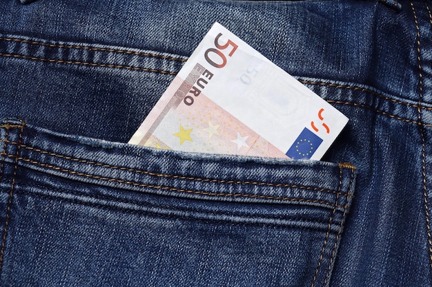 Gros plan d'un billet de 50 euros dans une poche de jean