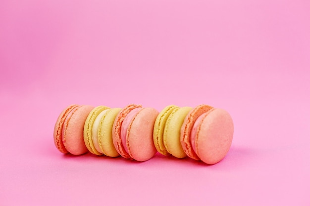 Gros plan d'un biscuit aux amandes jaunes ou de macarons aux couleurs pastel sur fond rose