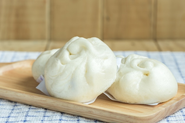 Gros plan blanc brioches à la vapeur sur un plateau en bois