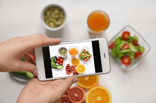 Gros plan d'un blogueur culinaire photographiant des fruits et légumes frais avec vue de dessus de téléphone portable