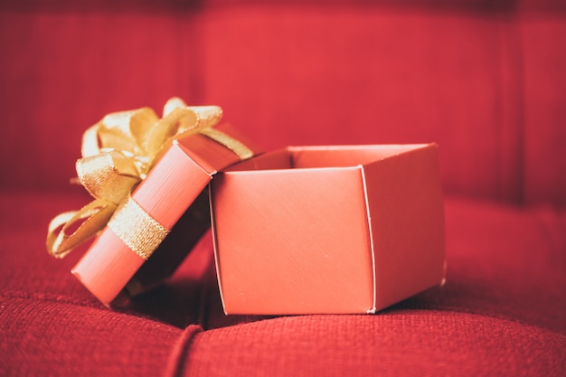 Gros plan d&#39;une boîte-cadeau sur un canapé rouge.