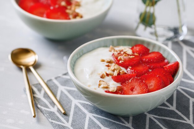 Gros plan de bols avec du yaourt à la noix de coco fraises et amandes fraîches Le concept de petit-déjeuner et un mode de vie sain de style scandinave