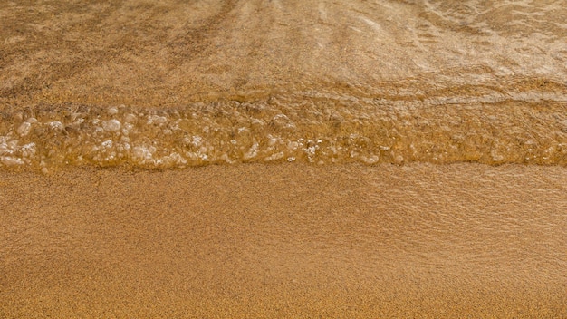 Gros plan d'un bord de l'eau et d'un fond de plage d'été de sable jaune avec espace de copie