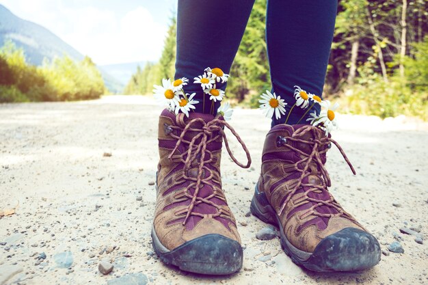 Gros plan sur les bottes de randonnée. touriste fille en bottes avec marguerites