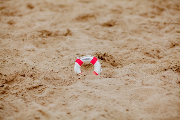 Gros plan d'une bouée de sauvetage miniature creuser dans le sable à la plage