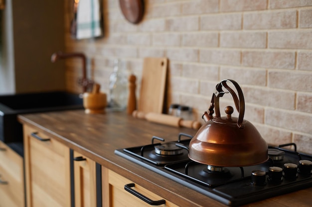 Gros plan d'une bouilloire en laiton rustique sur une cuisinière dans un espace de copie intérieur de cuisine moderne