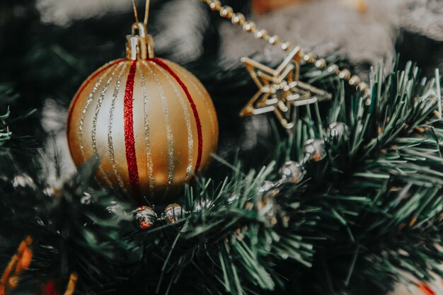 Gros plan d'une boule de Noël dorée sur la branche de pin