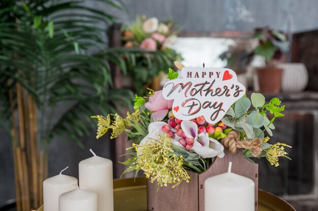 Gros plan d'un bouquet de roses roses avec une carte de fête des mères heureuse sur fond flou. Fleurs le jour spécial. Bougies et fleurs.