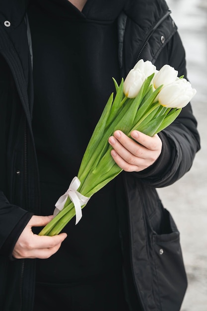 En gros plan, un bouquet de tulipes blanches dans les mains d'un homme