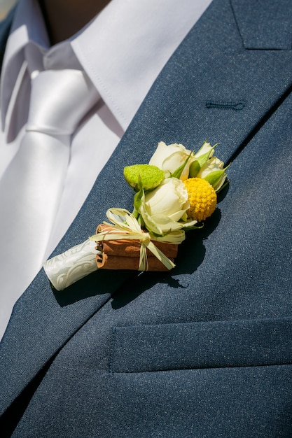 Gros plan d'une boutonnière du marié de roses beiges et cannelle