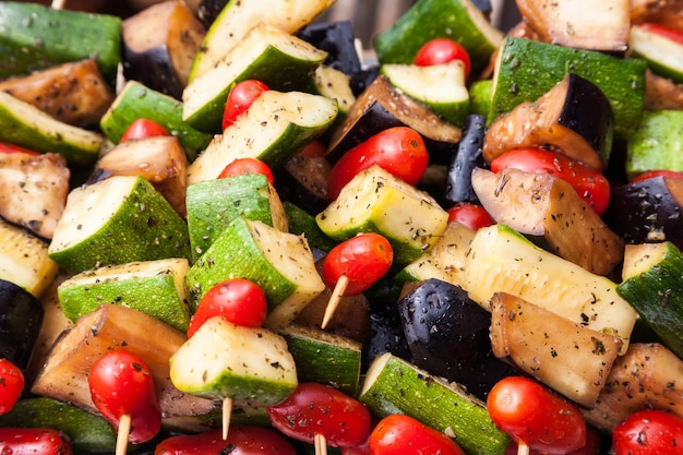 Gros plan de brochette de légumes frits sur des bâtonnets de bois courgettes tomates cerises aubergines et poivrons