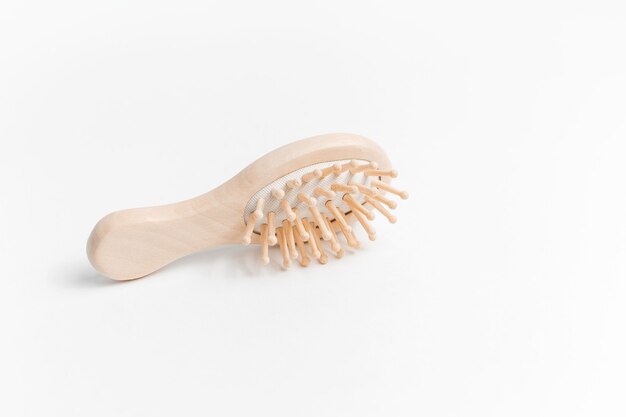 Gros plan d'une brosse à cheveux en bois sur blanc.