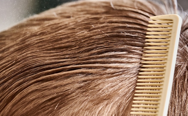 Gros plan de la brosse à cheveux masculine faisant une coupe de cheveux vagues de cheveux