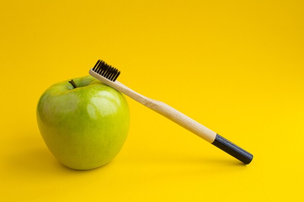 Photo gros plan sur la brosse à dents en bambou et pomme verte