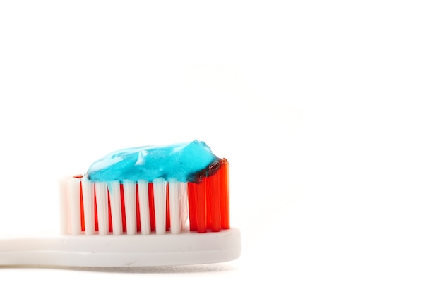 Gros plan de la brosse à dents avec du dentifrice sur un fond blanc.