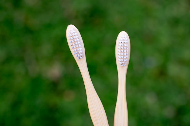 Gros plan de brosses à dents en bambou avec fond d'herbe verte brosses à dents en bambou biodégradables