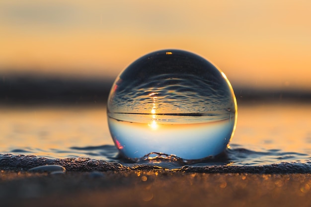 Gros plan d'une bulle d'eau reflétant le paysage marin derrière elle