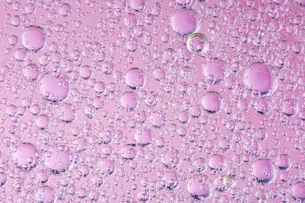 Gros plan des bulles d'huile dans l'eau sur fond rose image macro couleur douce abstrait papier peint lumineux