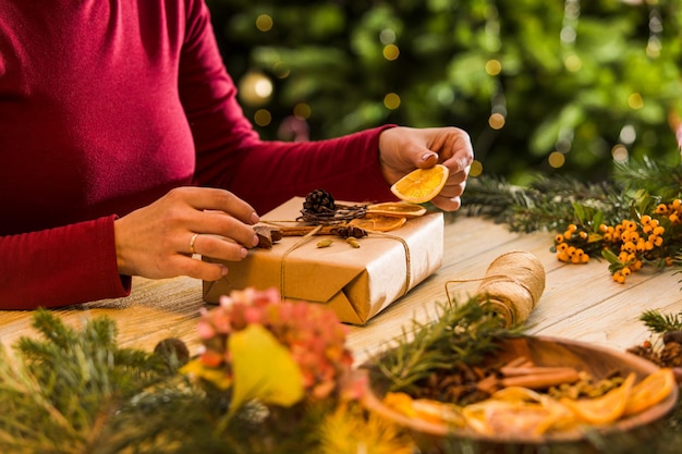 Gros plan sur un cadeau emballé artisanal aromatique Les mains d'une femme font des décorations de Noël pour une boîte cadeau