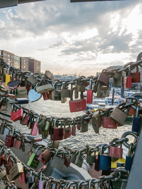 Photo en gros plan des cadenas d'amour attachés à la chaîne par la rivière dans la ville contre le ciel