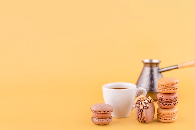 Gros plan sur une cafetière Americano coffee jezva et des biscuits aux amandes sur fond jaune