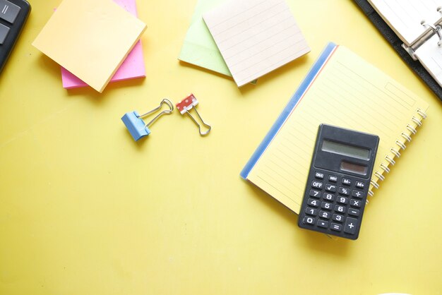 Gros plan sur une calculatrice bleue et un bloc-notes sur fond de couleur