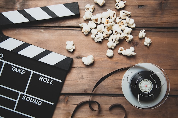 Photo gros plan de la caméra avec clap de bobine de film et pop-corn sur bois