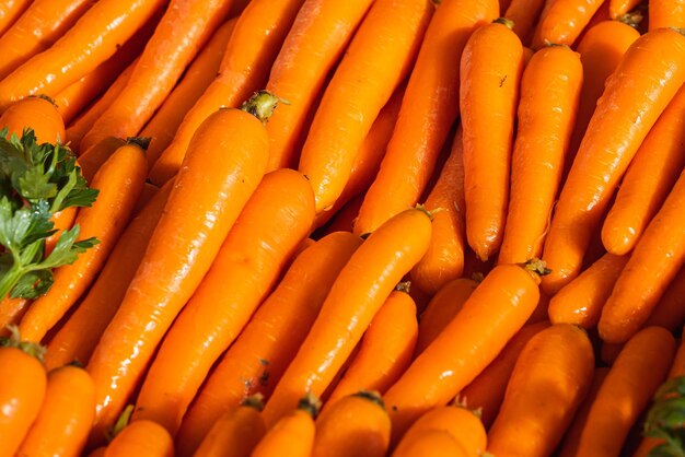 Gros plan de la carotte orange, arrière-plan. Variété de carotte fraîche cultivée en magasin. Nourriture savoureuse et saine
