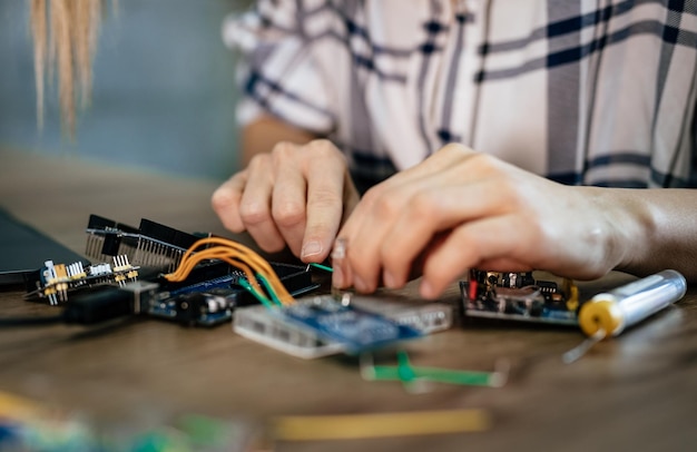 Gros plan d'une carte de circuit imprimé de soudure de mains féminines sur la table.