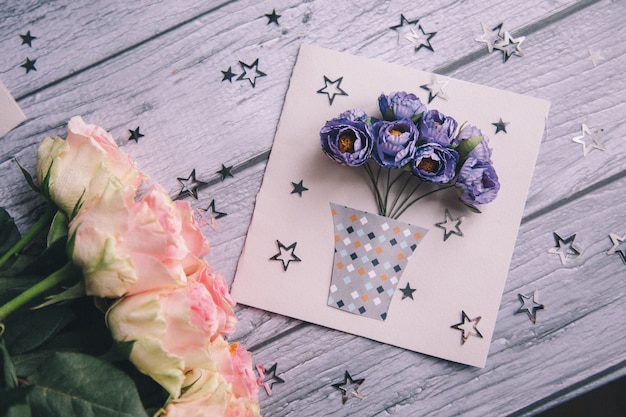 Photo gros plan d'une carte postale faite maison avec des fleurs bleues dans un pot.