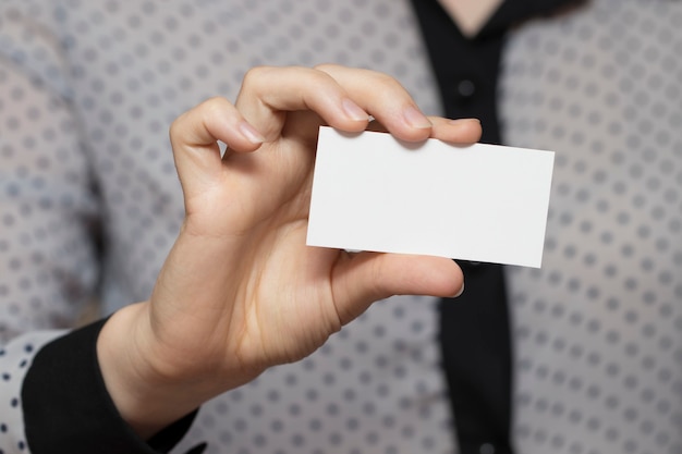 Gros plan d'une carte de visite vide dans la main d'une femme.