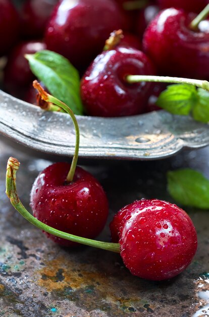 Gros plan sur les cerises noires et les feuilles de menthe fraîche dans un bol Pewt