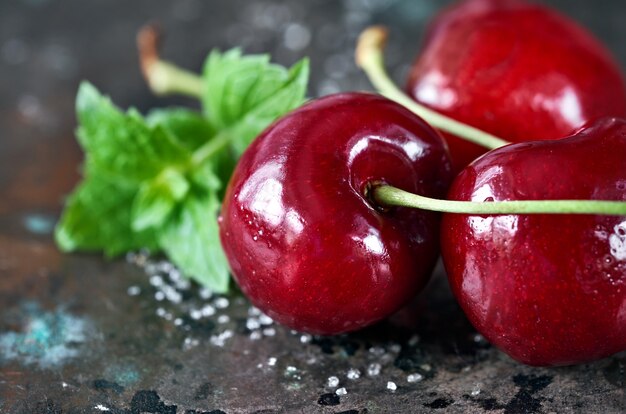 Gros plan sur les cerises noires et les feuilles de menthe fraîche sur dark