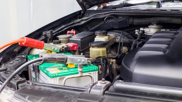 Gros plan Charger la batterie de la voiture avec de l'électricité via des câbles de démarrage.