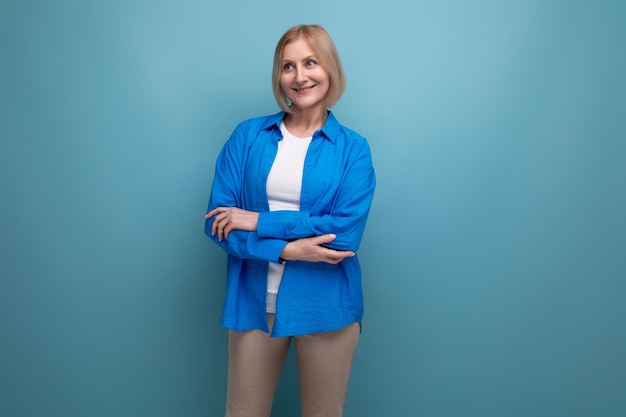 Gros plan d'une charmante femme mûre dans une chemise bleue sur fond bleu avec espace de copie