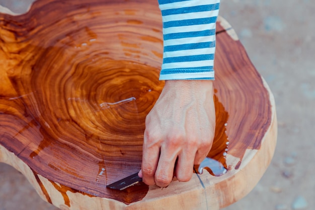 Gros plan charpentier versant de l'huile de lin sur une table en bois