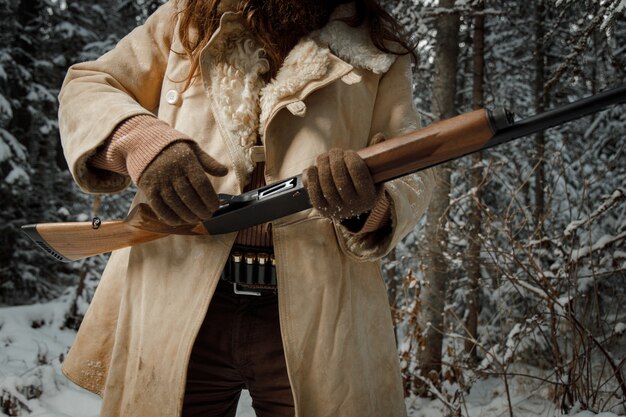 Gros plan chasseur en hiver vêtements vintage avec barbe en forêt avec pistolet