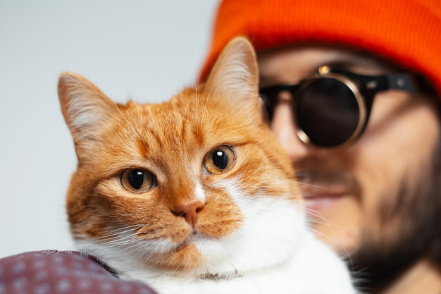 Gros plan d'un chat rouge-blanc dans les bras de son humain.