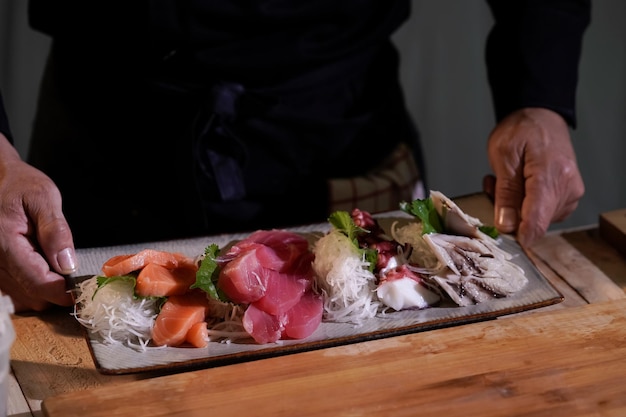 Gros plan d'un chef japonais se préparant à cuisiner des plats japonais Faire des sushis dans un restaurant japonais traditionnel sur une planche à découper