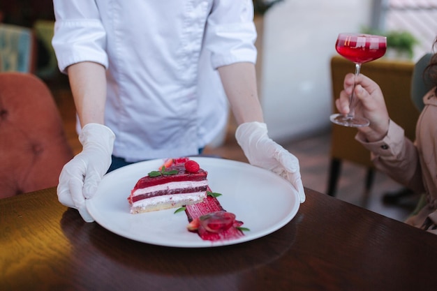 Gros plan sur un chef pâtissier apporter un gâteau à la fraise pour un client spécial Dessert sucré à la fraise pour femme