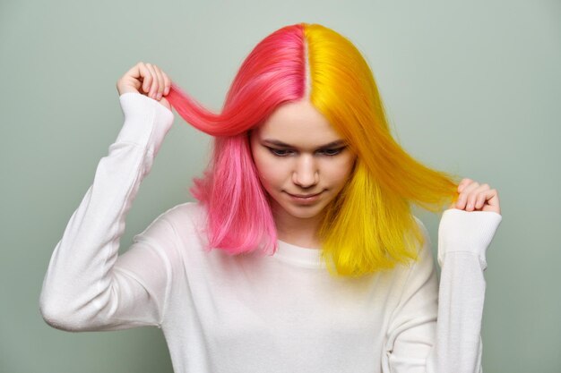 Gros plan sur les cheveux longs teints, modèle de beauté de mode fille montrant la coloration sur ses cheveux, fond de studio vert. Coloration professionnelle, beauté, mode, tendances