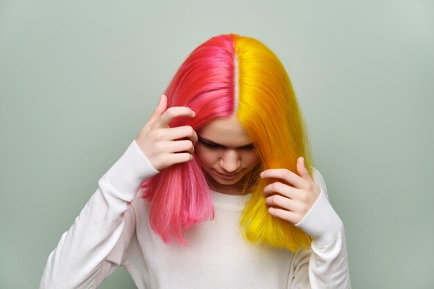 Gros plan sur les cheveux longs teints, modèle de beauté de mode fille montrant la coloration sur ses cheveux, fond de studio vert. Coloration professionnelle, beauté, mode, tendances