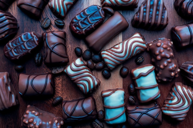 Gros plan de chocolats colorés et de grains de café torréfiés sur fond de bois