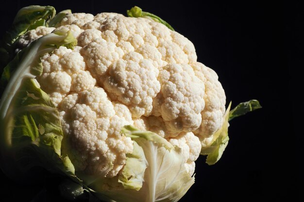 Gros plan de chou-fleur sur fond noir Éclairage latéral Tête de chou frais Légumes verts