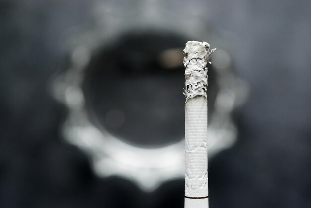 Gros plan d'une cigarette allumée sur fond sombre