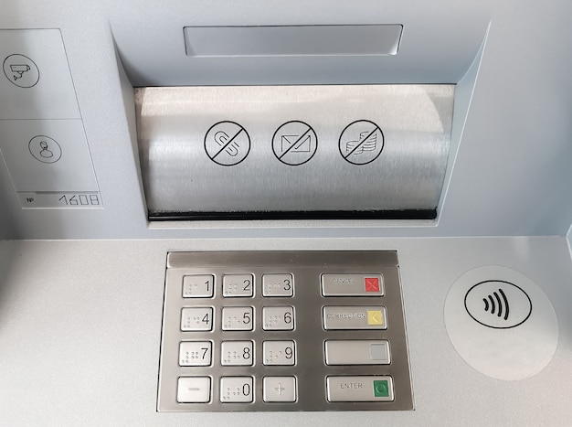 Gros plan sur un clavier ATM et un compartiment pour recevoir et émettre des billets.